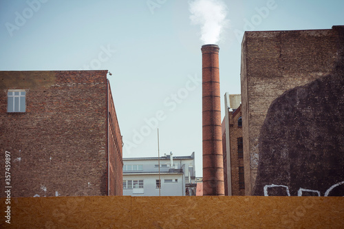 Smoke emitted from an industrial brick chimney in an old factory building
