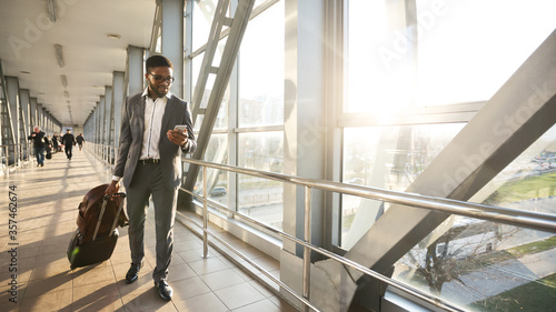 фотографія African Businessman Texting On Cellphone Walking In Airport Indoor, Panorama