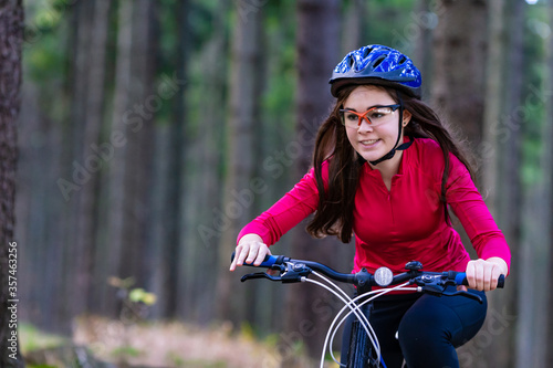 Healthy lifestyle - teenage girl biking in forest 