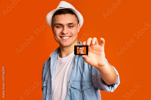 Cheerful young man tourist using action camera