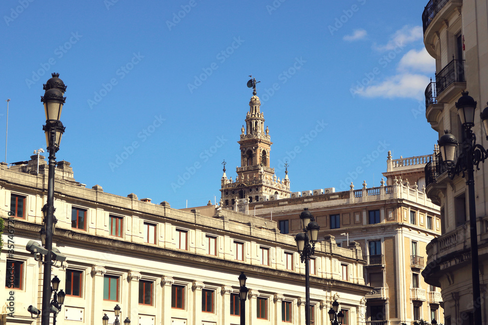landscape with the view of the top of Giralda tower, in Seville, between the buildings with a clean blue sky