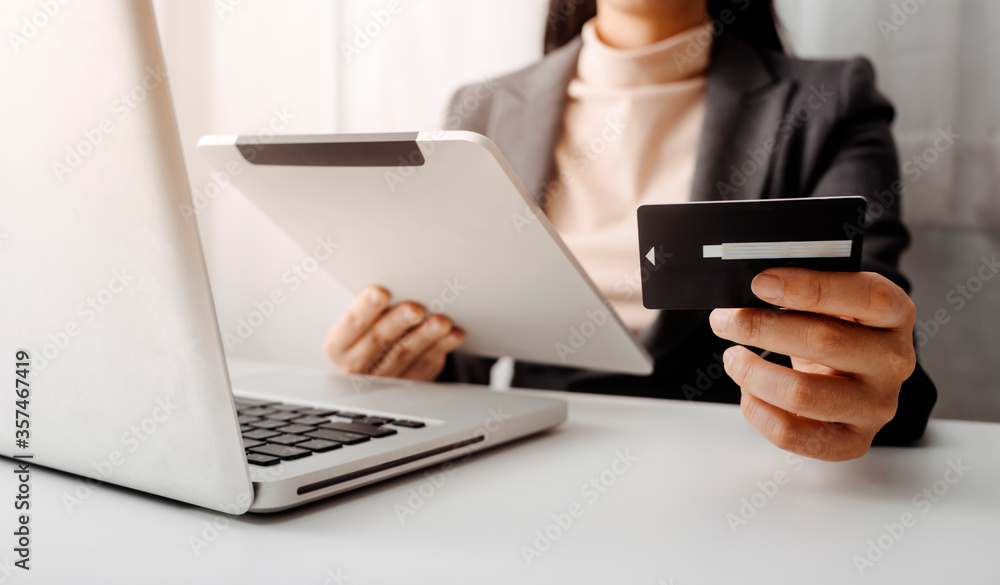 businesswoman hand using smart phone, tablet payments and holding credit card online shopping, omni channel, digital tablet docking keyboard computer at office in sun light businesswoman hand using smart phone, tablet payments and holding credit card online shopping, omni channel, digital tablet docking keyboard computer at office in sun light