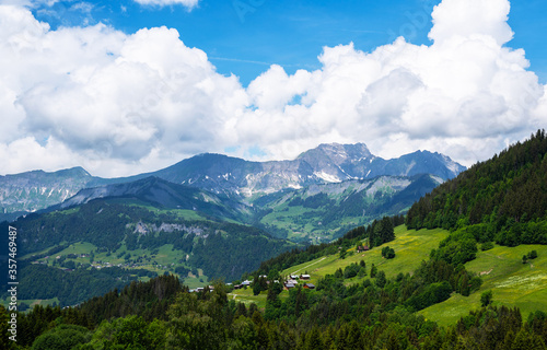 Amazing summer panorama with mountains, small village, green meadows and cloudly blue sky in Swiss Alps. Oberland, Switzerland.