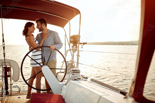 Man and woman sailing on a boat at vacation at romantic sunset. © luckybusiness