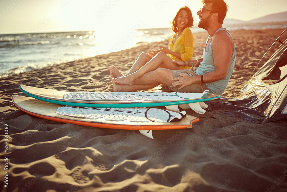 Obraz premium Young man and woman camping on the beach during the sunset.