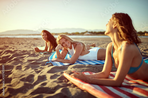 Three young  woman lying on the beach during the summer and sunbathing. photo