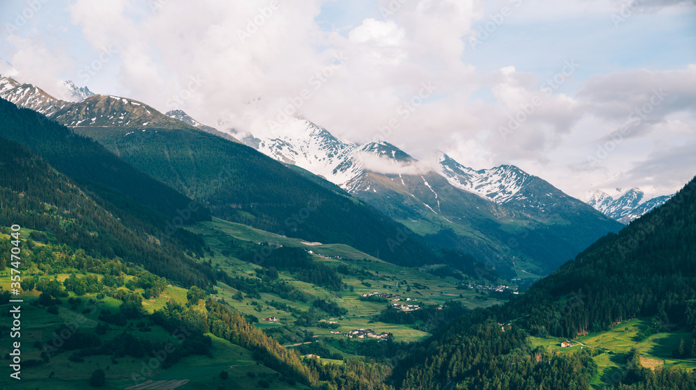 Naklejka premium Scenic view of beautiful Swiss Alps mountains. Canton du Valais, Switzerland. Picturesque Alpine village in background. Swiss Alps with snow on top. Switzerland in summer. Alpine landscape