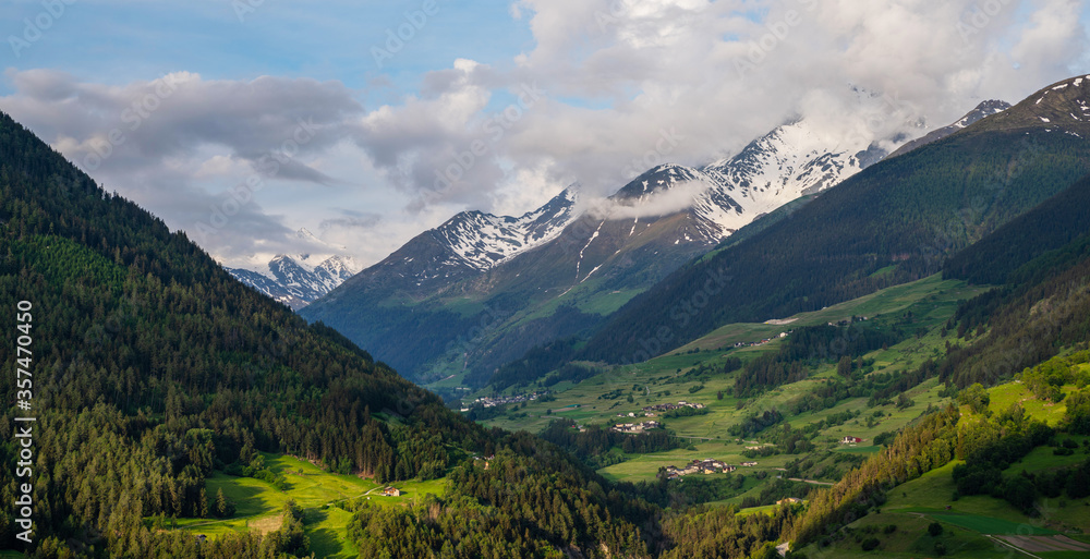 Fototapeta premium Scenic view of beautiful Swiss Alps mountains. Canton du Valais, Switzerland. Picturesque Alpine village in background. Swiss Alps with snow on top. Switzerland in summer. Alpine landscape