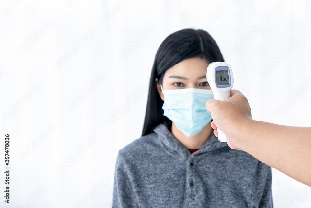 Blurred soft images of People using infrared Thermometer For measuring the temperature of women Wearing a surgical mask, to screen the patients, to health care concept.