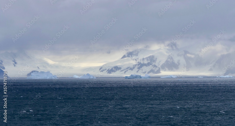 Iceberg in antarctic ocean and before glacier landscape, Antarctica