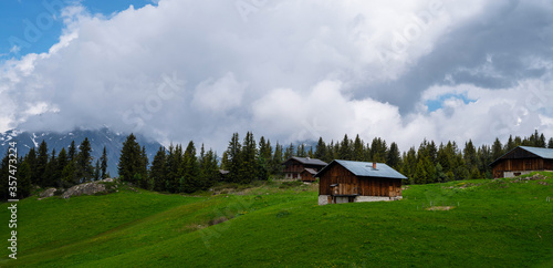 Beautiful view of scenic mountain landscape in the Alps with traditional old mountain chalet and fresh green meadows with blue sky and clouds in spring. © eskstock