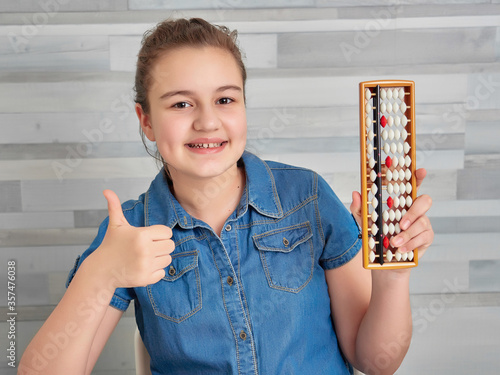 Happy girl holding abacus over light background. Mental arithmetic school. Kids development, skill at mental arithmetic.