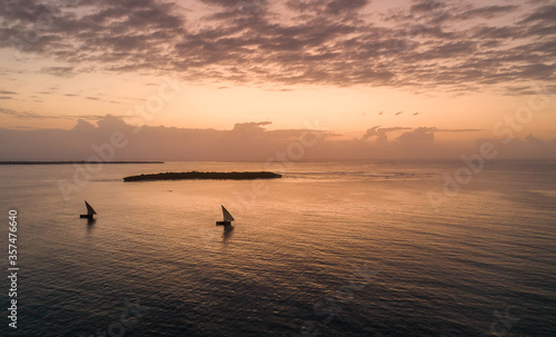 Dhow boats sailing in front of islands during sunrise © Rassie