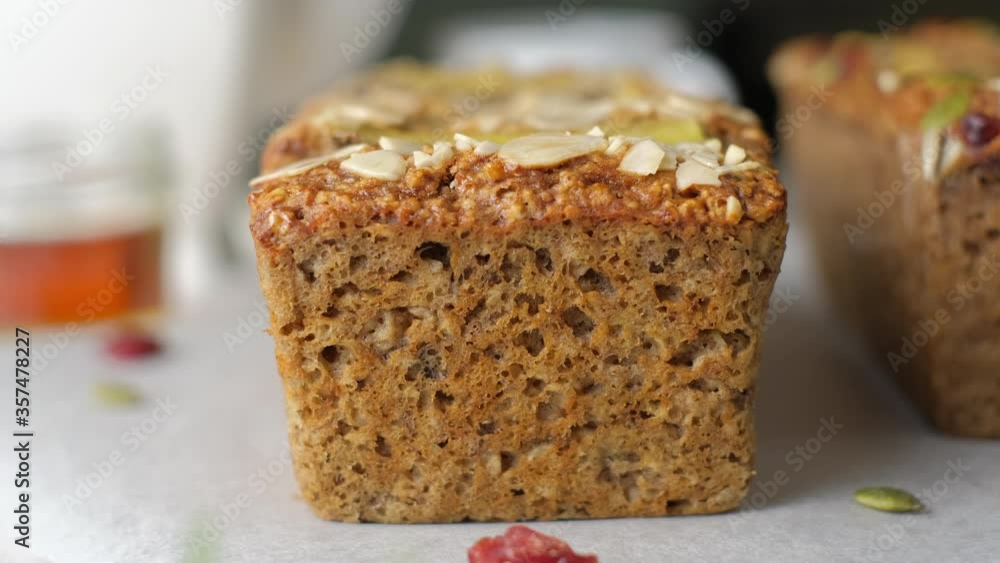 Loaf of Vegan Oatmeal Banana Bread topped with nut, seed, almond slide and banana set on cafe table. Loaf of Vegan Oatmeal Banana Bread topped with nut, seed, almond slide and banana set on cafe table.