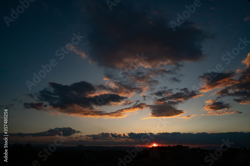 Obraz na płótnie Black evening clouds at sunset. Clouds beat off red sunset light from the sun. w salonie