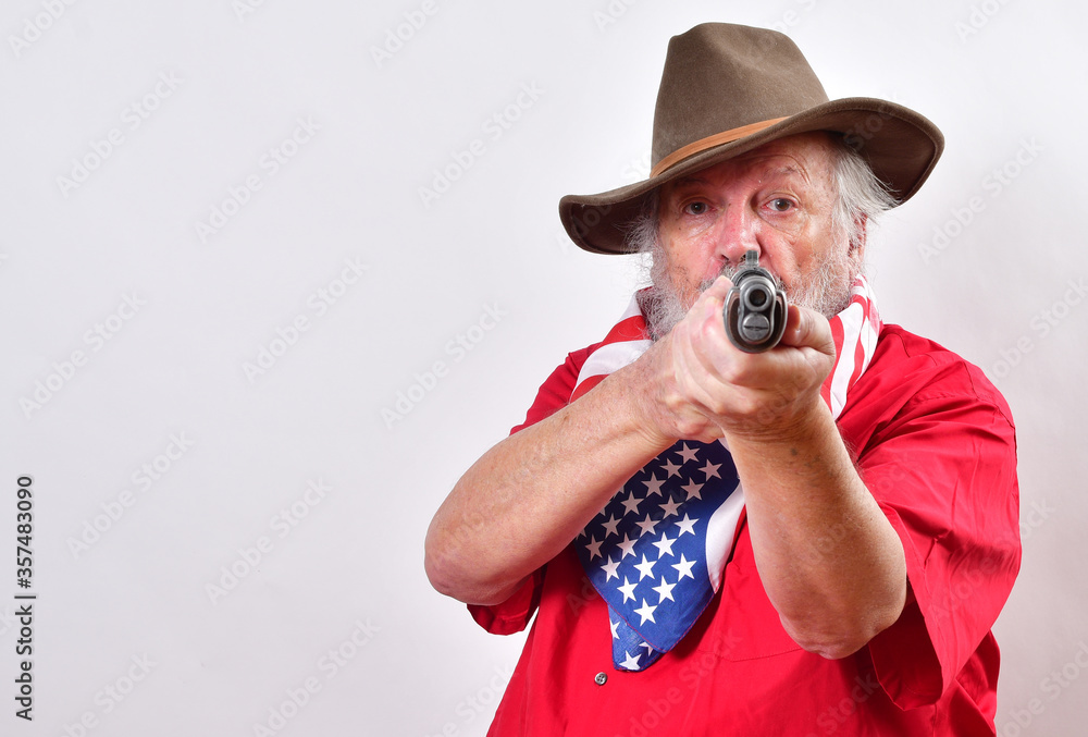 Determined looking old man with a sawed off rifle, wearing patriotic colors, and a floppy western hat pointing his weapn right at the camera..Crazy old man has that "Get off my lawn" look - obrazy, fototapety, plakaty 