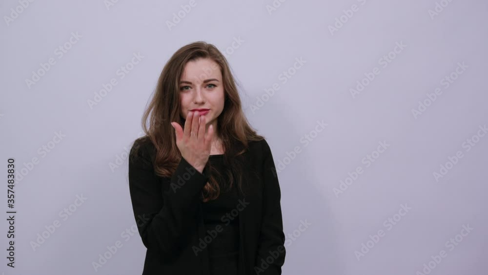 Sending sweet air kiss blowing red lips stretching hand for taking selfie demonstrate feelings. Young attractive woman brunette in a black t-shirt and sweater on white background Sending sweet air kiss blowing red lips stretching hand for taking selfie demonstrate feelings. Young attractive woman brunette in a black t-shirt and sweater on white background