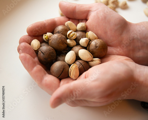 A handful of nuts in men's palms. A handful of macadamia and pistachios
