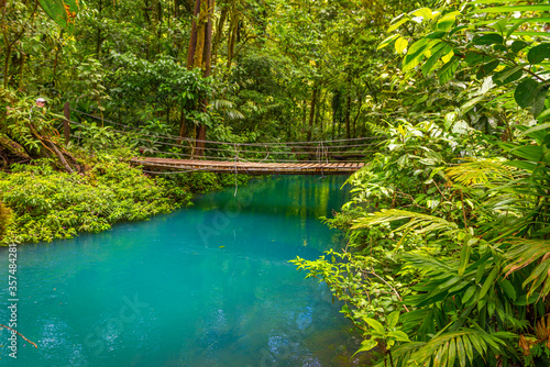 Fototapeta Naklejka Na Ścianę i Meble -  Rio Celeste with turquoise, blue water and small wooden bridge across the river Tenorio national park Costa Rica. Central America.
