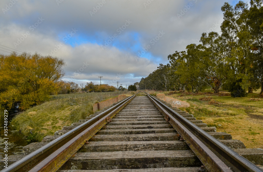 estación y vías del tren rodeada de arboles y arroyo