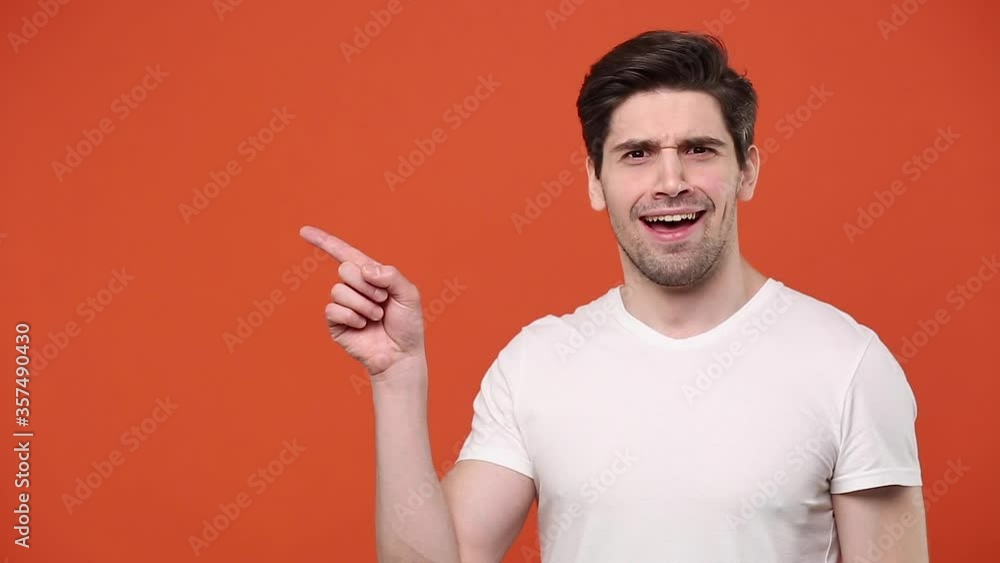 Young fun guy 20s 30s years old in white t-shirt isolated on orange background studio. People lifestyle concept. Looking camera pointing showing fingers hands on workspace copy space mock up template Young fun guy 20s 30s years old in white t-shirt isolated on orange background studio. People lifestyle concept. Looking camera pointing showing fingers hands on workspace copy space mock up template