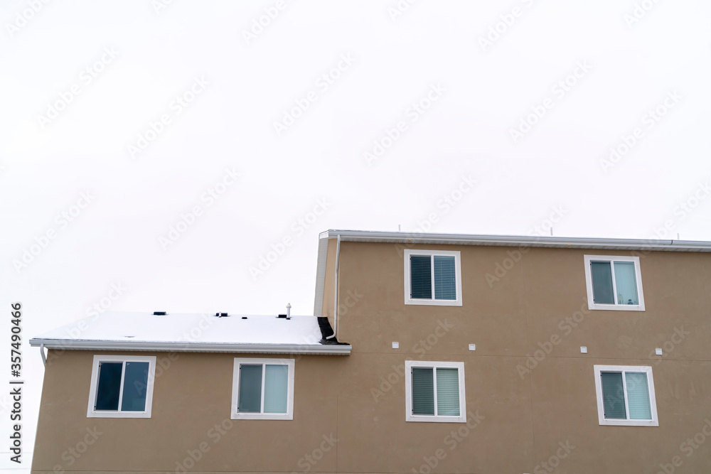 Exterior view of building with snowy pitched roof over wall with sliding windows Exterior view of building with snowy pitched roof over wall with sliding windows