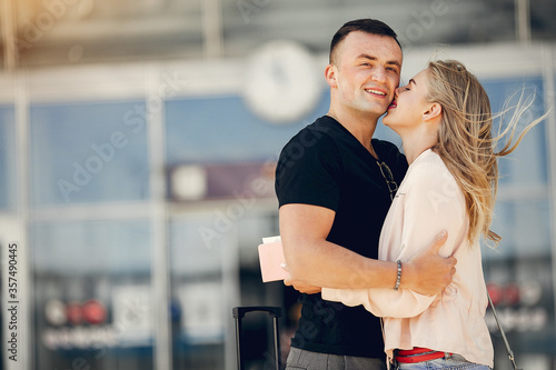 Couple in a airport. Beautiful blonde in a white jacket. Man in a black t-shirt