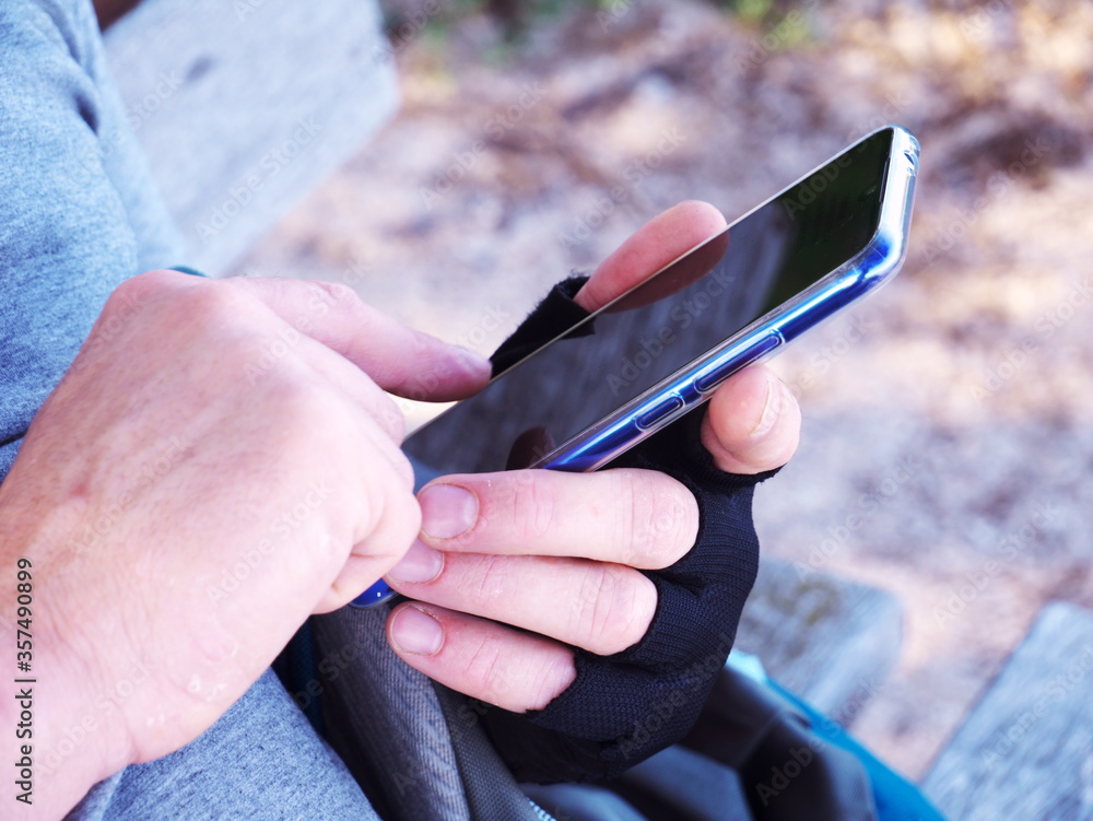 Close-up of the hands of an athlete on a bicycle using his phone during his break