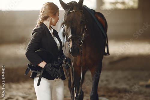 Woman near horse. Rider in a black uniform © prostooleh