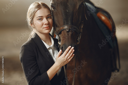 Woman near horse. Rider in a black uniform