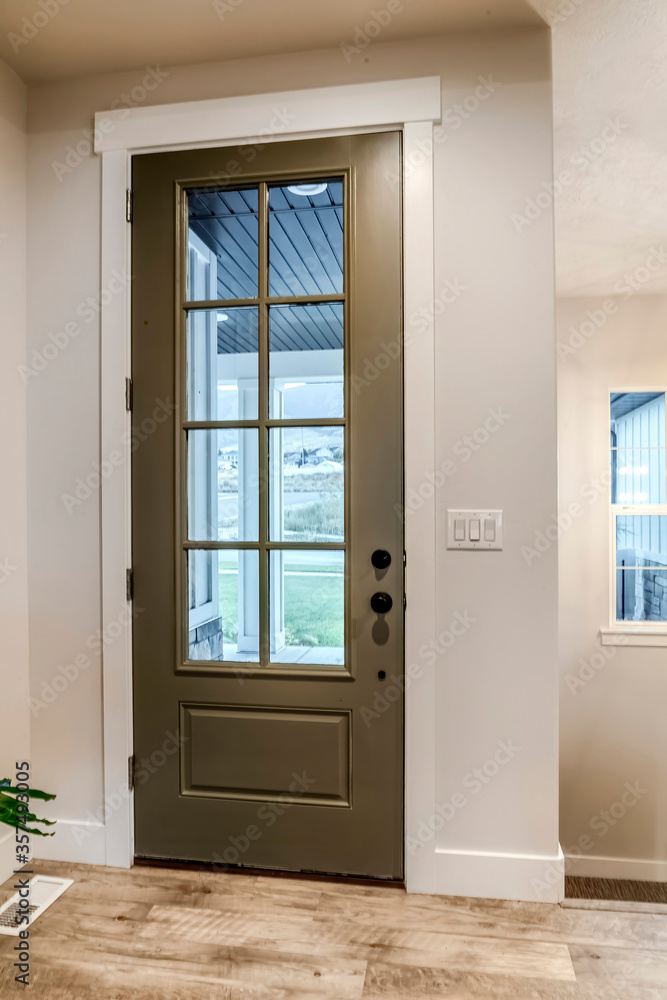 Hinged front door with glass pane viewed from interior of home with wood floor Hinged front door with glass pane viewed from interior of home with wood floor