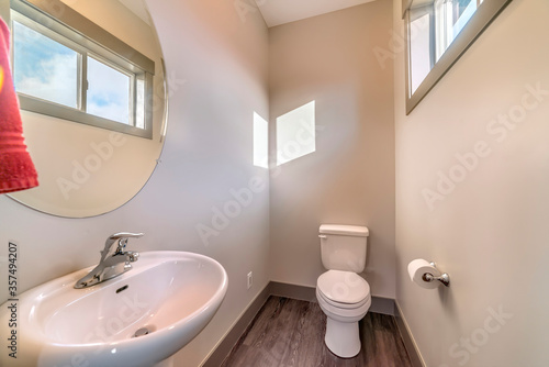 Bathroom of home with free standing sink round mirror toilet and wooden floor