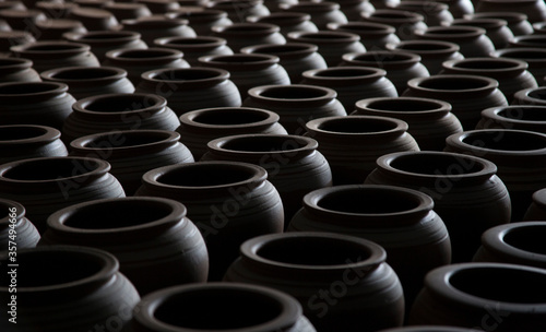 Hundreds of handmade pots in the workshop. Shadow and light together.