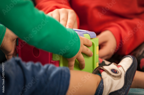 Baby boy and small girl are playing with cubic toys. Childhood and friendship. Hands are visible mainly. Colourful toys and children playing with those toys.