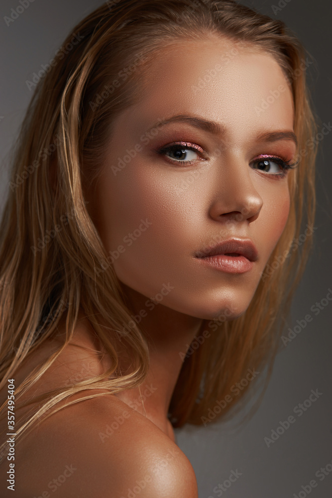 Obraz premium Closeup face fashion beauty portrait of young beautiful caucasian blonde woman with straight hair and makeup posing against gray background.
