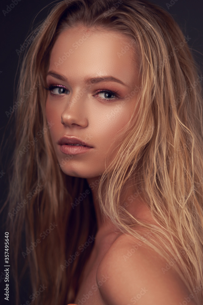 Closeup face portrait of young pretty caucasian woman with long blonde woman looking in camera and posing against gray background. Shallow DOF. Closeup face portrait of young pretty caucasian woman with long blonde woman looking in camera and posing against gray background. Shallow DOF.