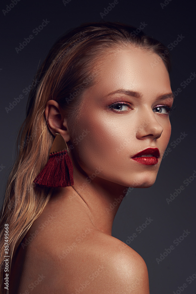 Fototapeta premium High fashion closeup beauty portrait of young stunning woman with long straight blonde hair, perfect makeup and red lips against gray background