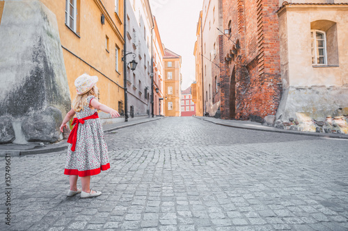 Little girl in dress and hat walking through the streets of the old town in Warsaw, Poland © Irving Sandoval
