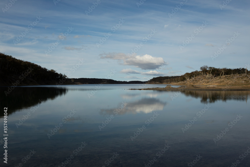 View of the pure water lake in the forest, under a beautiful sky and its reflection in the water surface. 