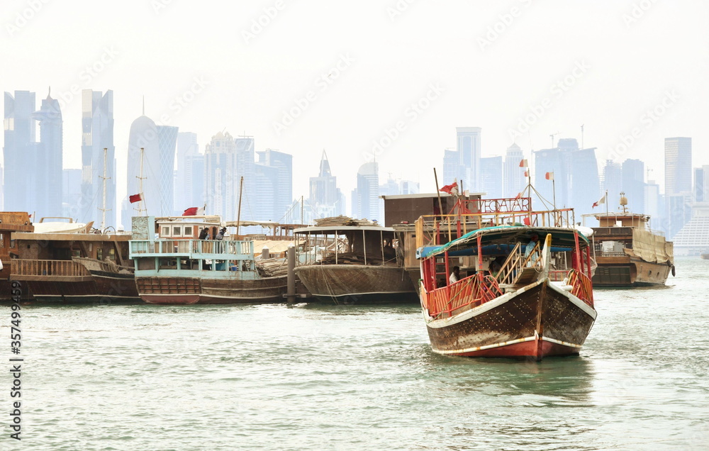 Traditional dhow boat in Doha, with buildings in the background.