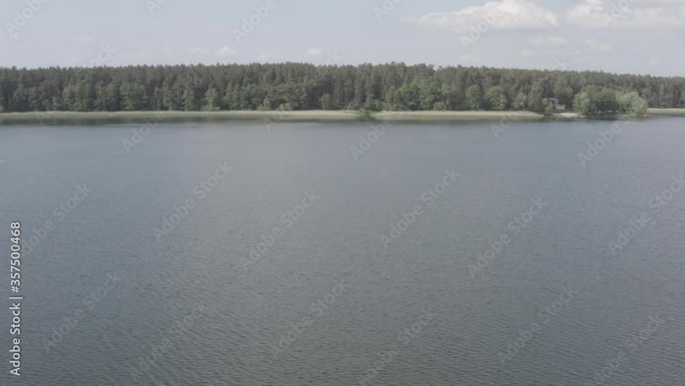 Fly over the lake towards shore covered with forest, 4k unedited Dlog-M flat profile footage Fly over the lake towards shore covered with forest, 4k unedited Dlog-M flat profile footage