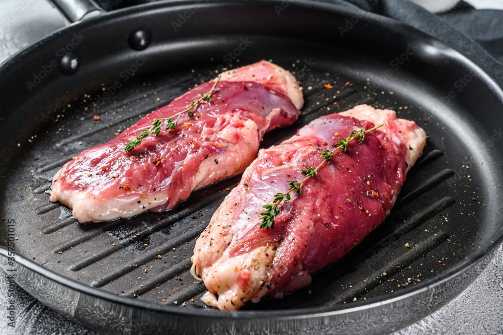 Raw duck Breasts on a grill pan. Organic poultry meat. Gray background. Top view