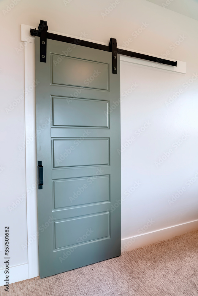 Closed sliding gray panel door with black handle against white wall of home Closed sliding gray panel door with black handle against white wall of home