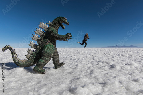 Woman playing in salt flats escaping from dinosaur