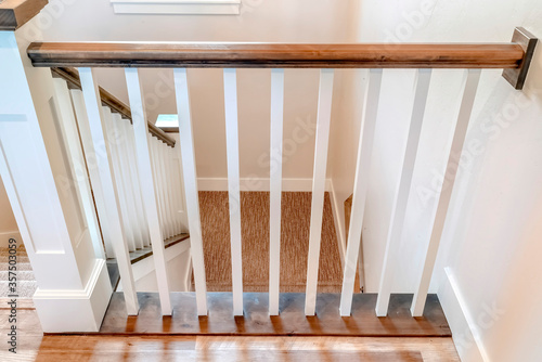 Canvas Print U shaped stairway of home with brwon handrail supported by white balusters