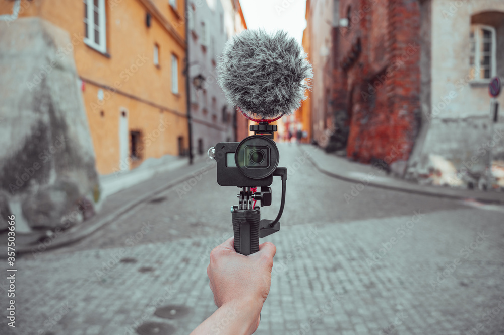 Hand holding a camera with microphone, vlogger with camera recording a video blog, content creation tools