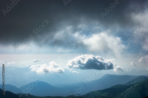 Summer rain in the mountains. Dramatic clouds and mountains silhouette. Lonely cloud