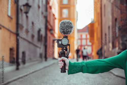 Obraz na płótnie Hand holding a camera with microphone, vlogger with camera recording a video blog, content creation tools w salonie