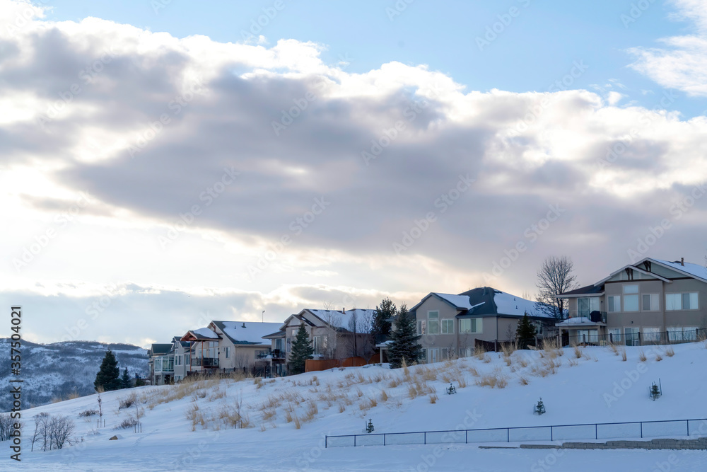 Clouds and blue sky over homes on pristine terrain of Wasatch Mountains