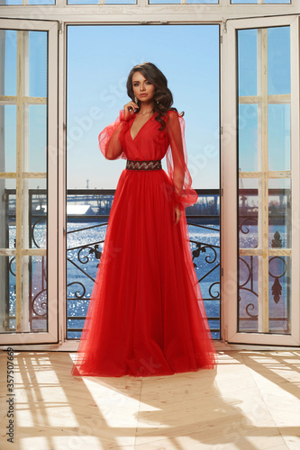 Young beautiful stunning girl in long red dress posing in interior with open door and view on sunny blue sky. Woman in elegant ball gown Free Download Young beautiful stunning girl in long red dress posing in interior with open door and view on sunny blue sky. Woman in elegant ball gown - GFXLoad